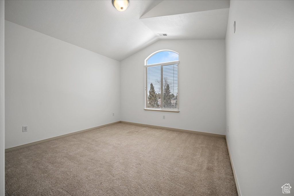 Empty room featuring lofted ceiling and carpet flooring