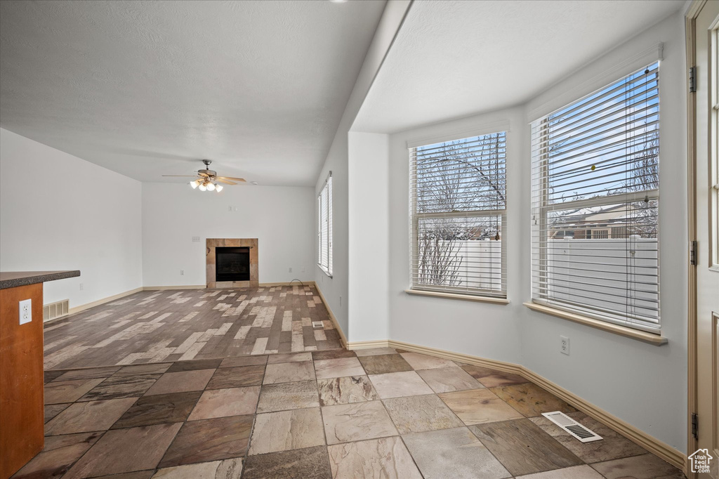 Unfurnished living room with ceiling fan and a tile fireplace