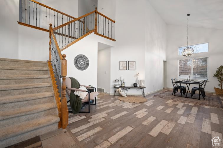 Entrance foyer featuring wood finished floors, baseboards, a high ceiling, stairs, and a notable chandelier