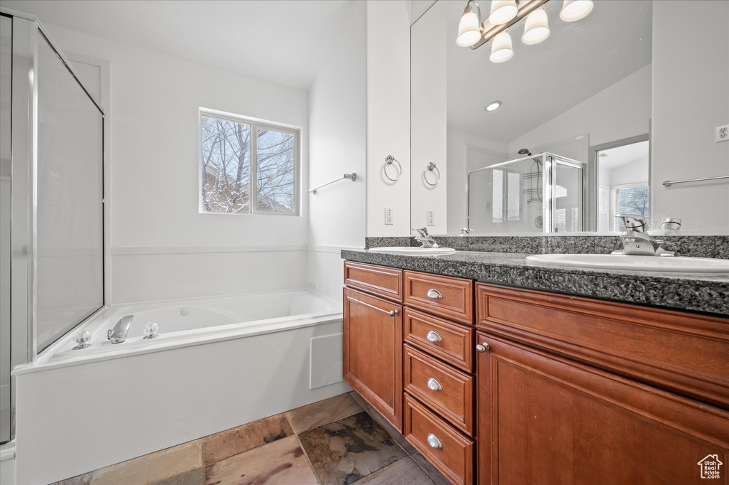 Bathroom featuring vanity, vaulted ceiling, shower with separate bathtub, and a healthy amount of sunlight