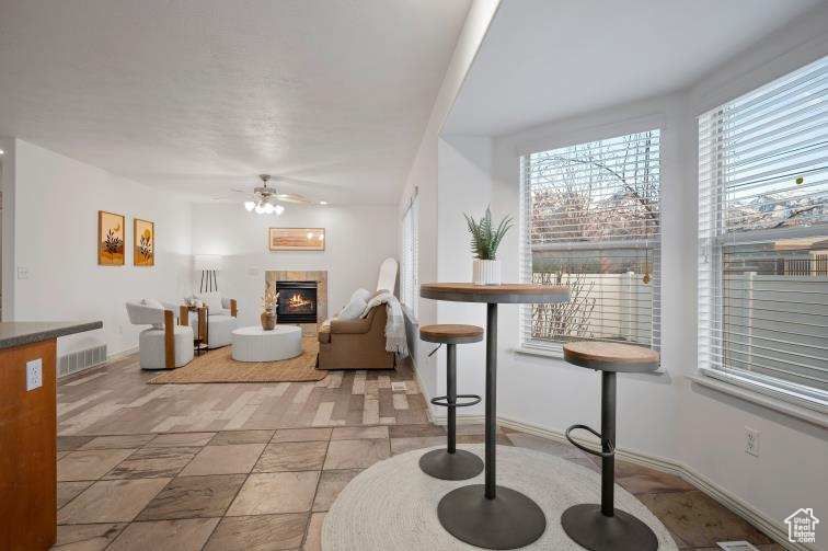 Living room with visible vents, baseboards, ceiling fan, and a tiled fireplace