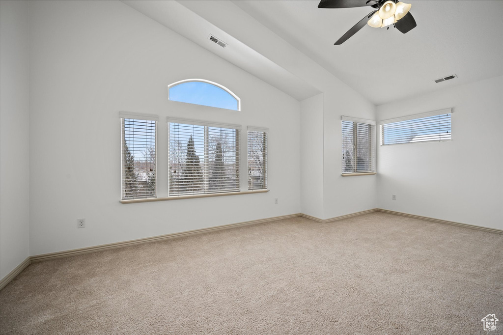 Carpeted spare room featuring high vaulted ceiling and ceiling fan