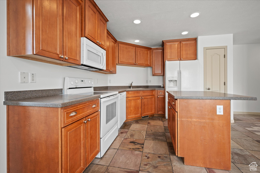 Kitchen featuring white appliances, a center island, and sink