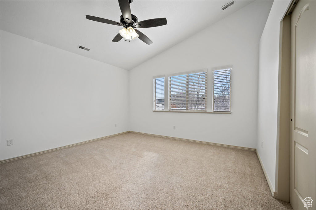 Spare room with lofted ceiling, light carpet, and ceiling fan