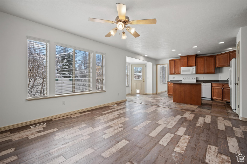 Kitchen featuring white appliances, hardwood / wood-style floors, a kitchen island, and a wealth of natural light