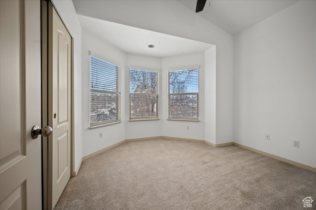 Carpeted spare room with ceiling fan and lofted ceiling