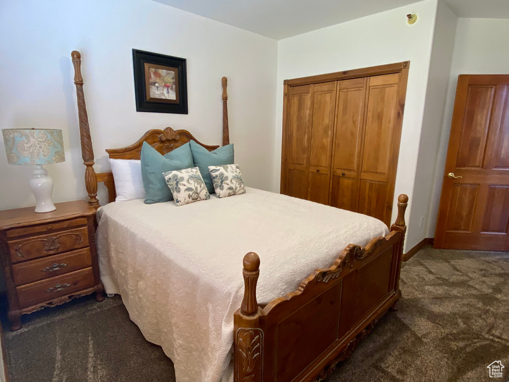 Bedroom with dark colored carpet and a closet