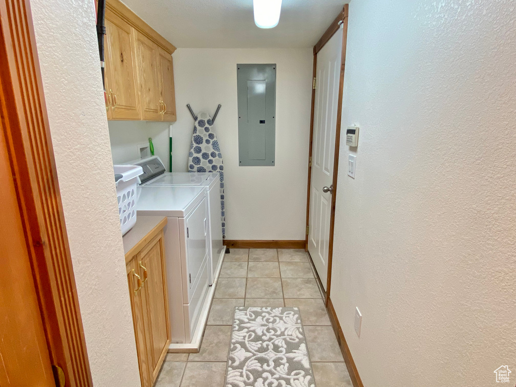 Washroom with independent washer and dryer, electric panel, cabinets, and light tile patterned flooring