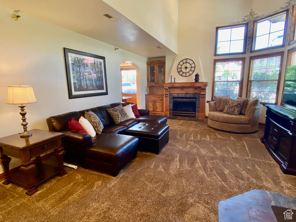 Carpeted living room with a towering ceiling and a tile fireplace