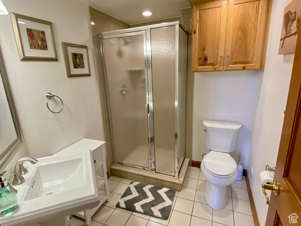 Bathroom featuring tile patterned flooring, a shower with shower door, and toilet