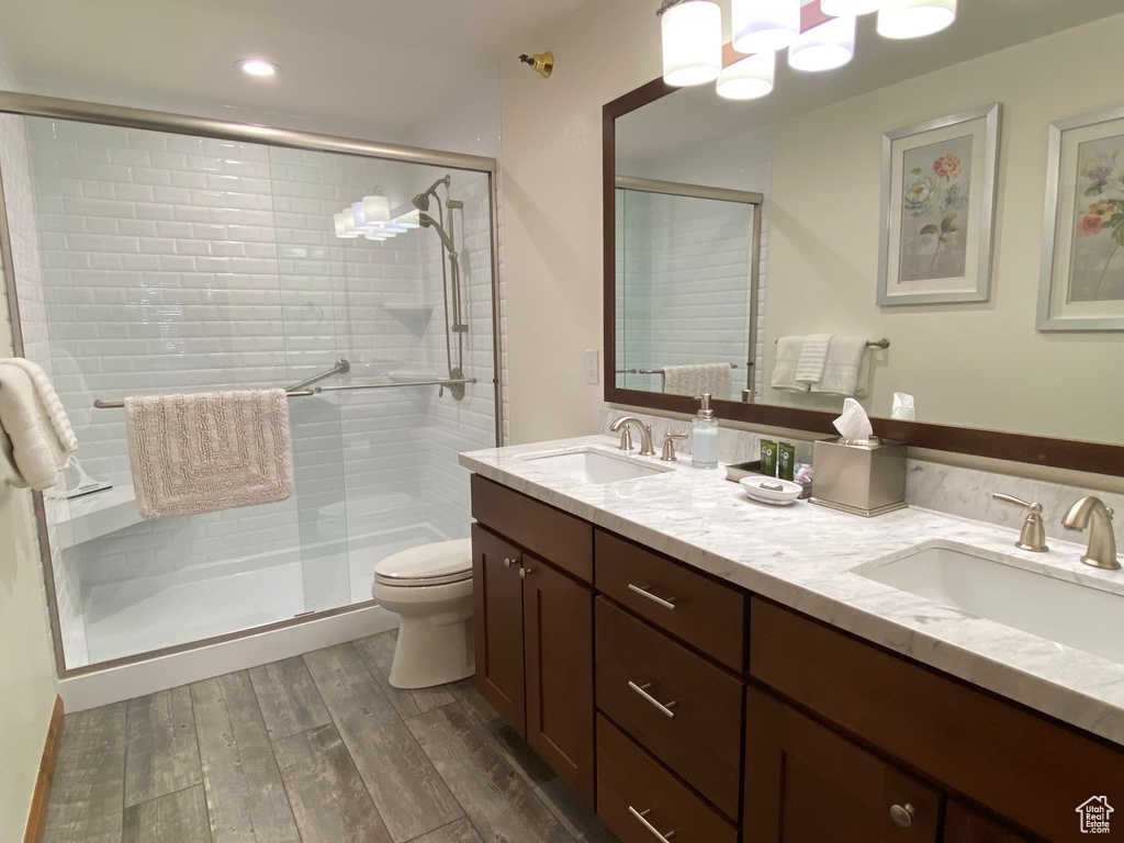 Bathroom with vanity, hardwood / wood-style floors, a shower with shower door, and toilet