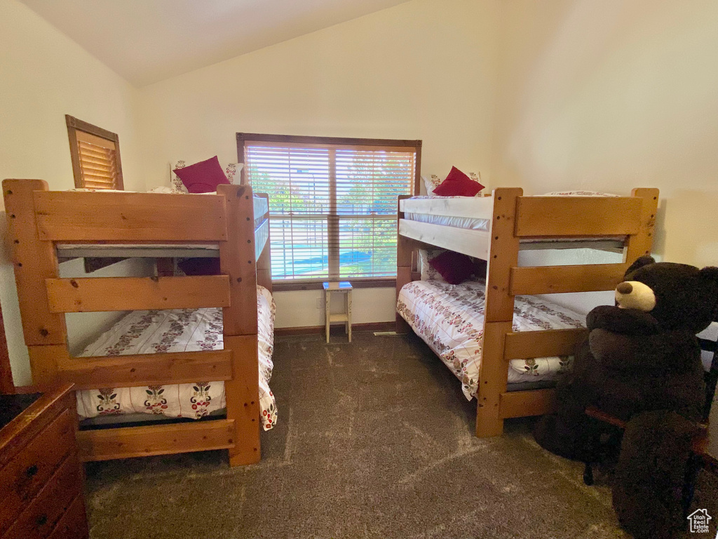 Bedroom featuring dark carpet and vaulted ceiling