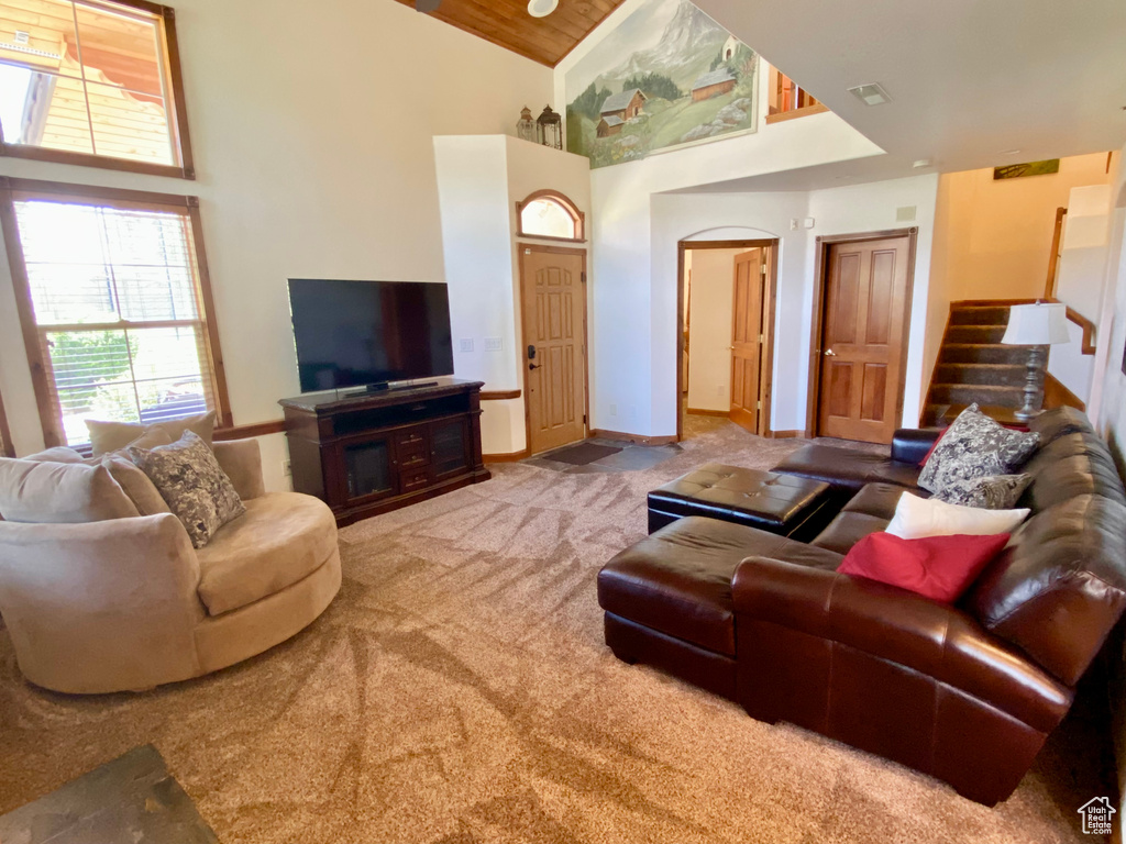 Carpeted living room featuring high vaulted ceiling and wooden ceiling