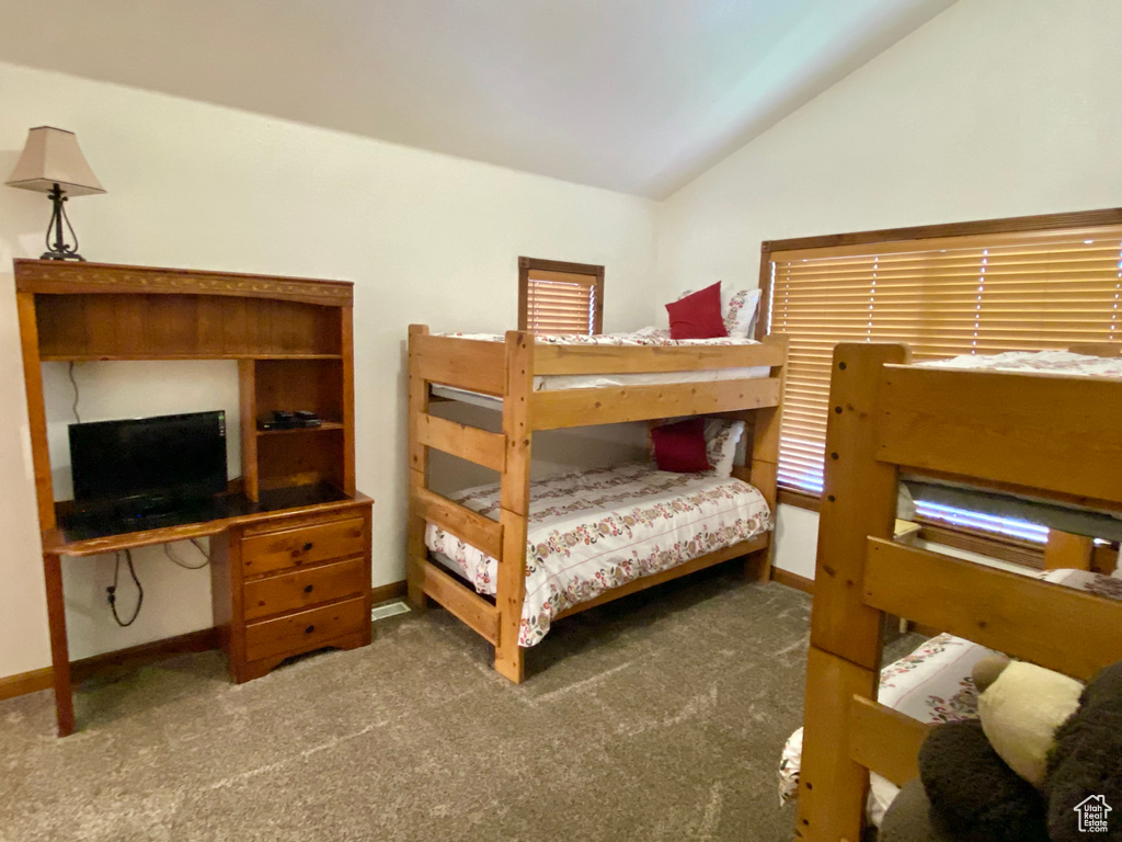 Bedroom with dark colored carpet and lofted ceiling