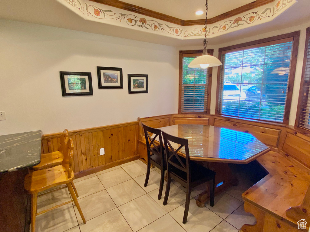 Tiled dining room with a tray ceiling and ornamental molding