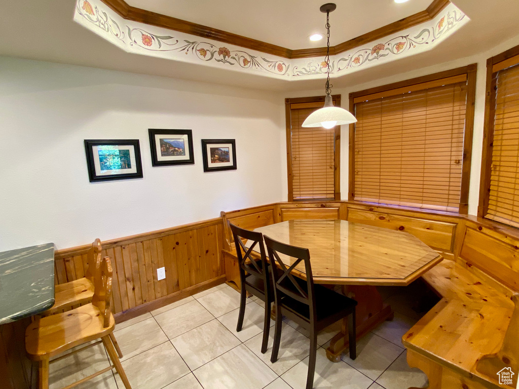 Dining room featuring crown molding, light tile patterned floors, and a tray ceiling