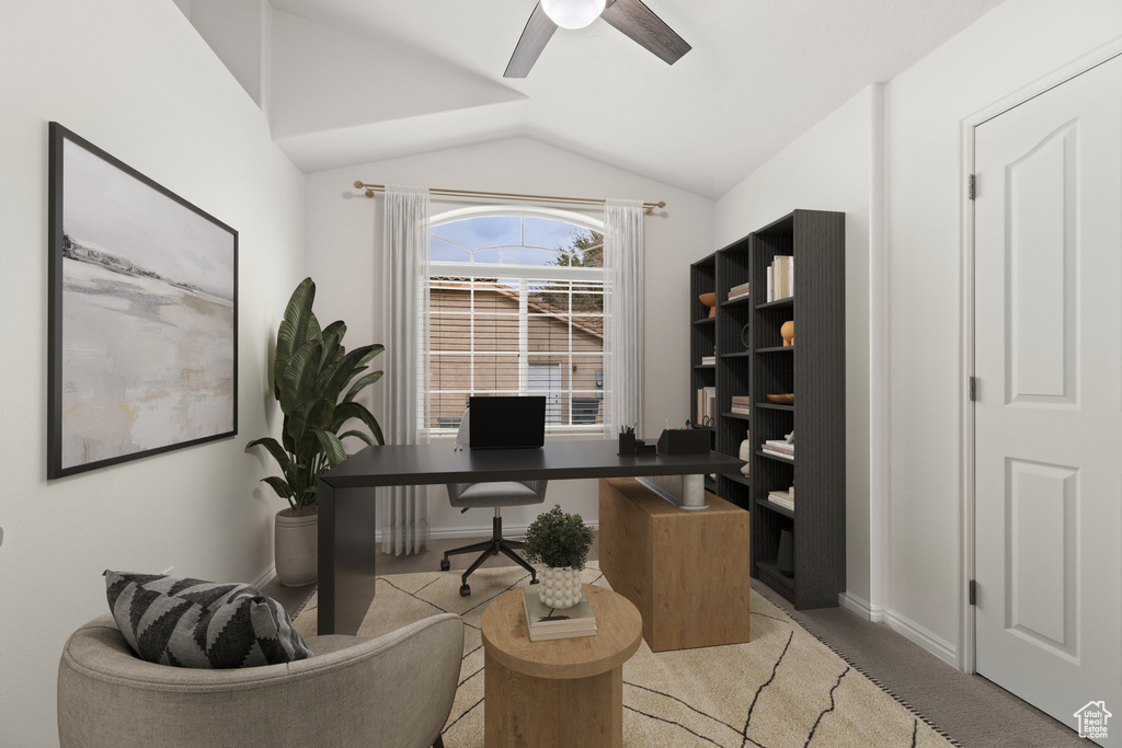 Home office featuring lofted ceiling, a ceiling fan, light colored carpet, and baseboards