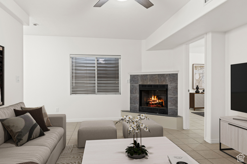 Living room with light tile patterned flooring, a fireplace, ceiling fan, and baseboards
