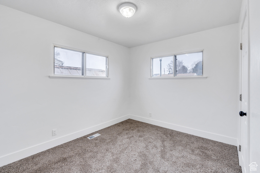 Empty room featuring plenty of natural light and carpet flooring