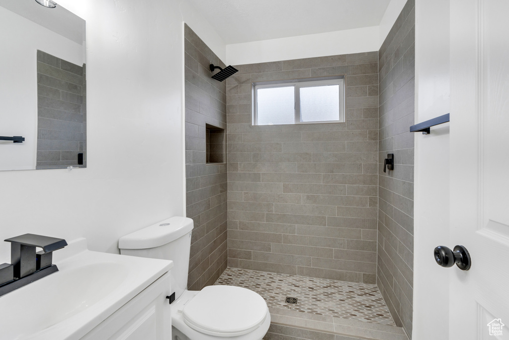 Bathroom with tiled shower, vanity, and toilet