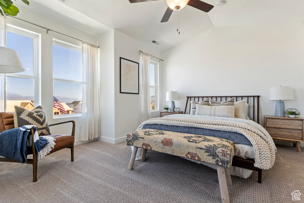 Carpeted bedroom featuring vaulted ceiling and ceiling fan