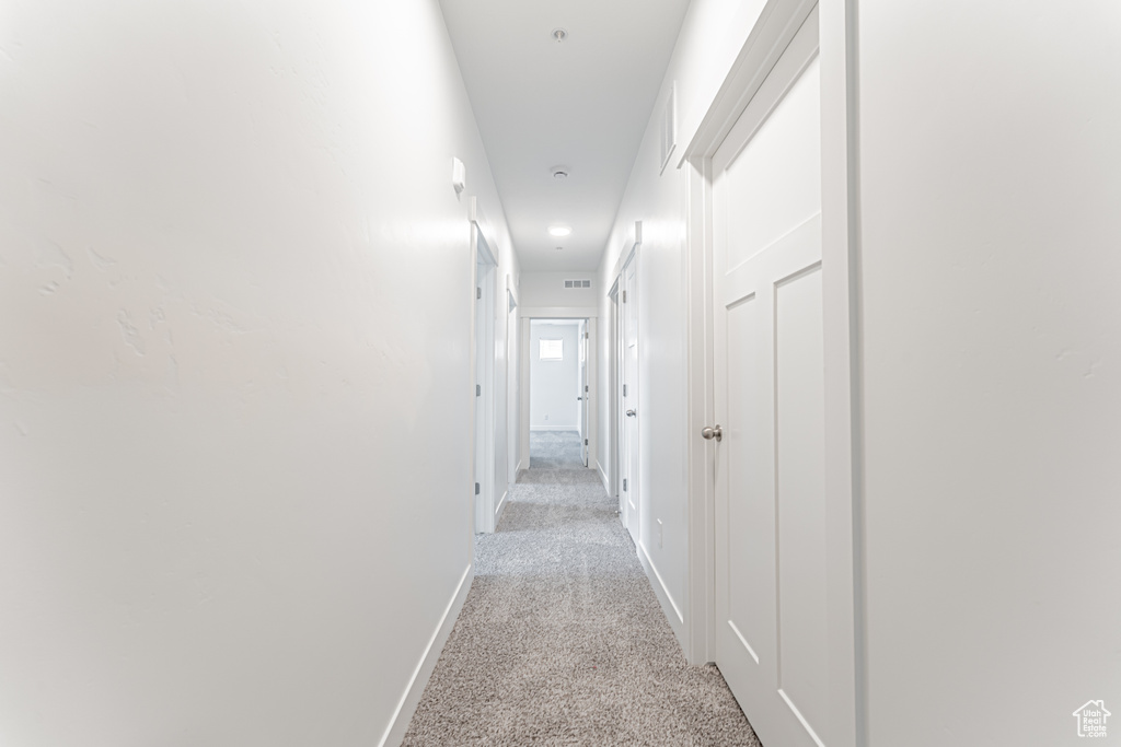 Hall with light colored carpet and baseboards
