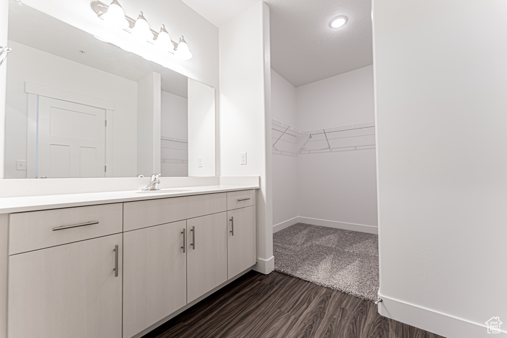 Bathroom featuring vanity, wood finished floors, and a walk in closet