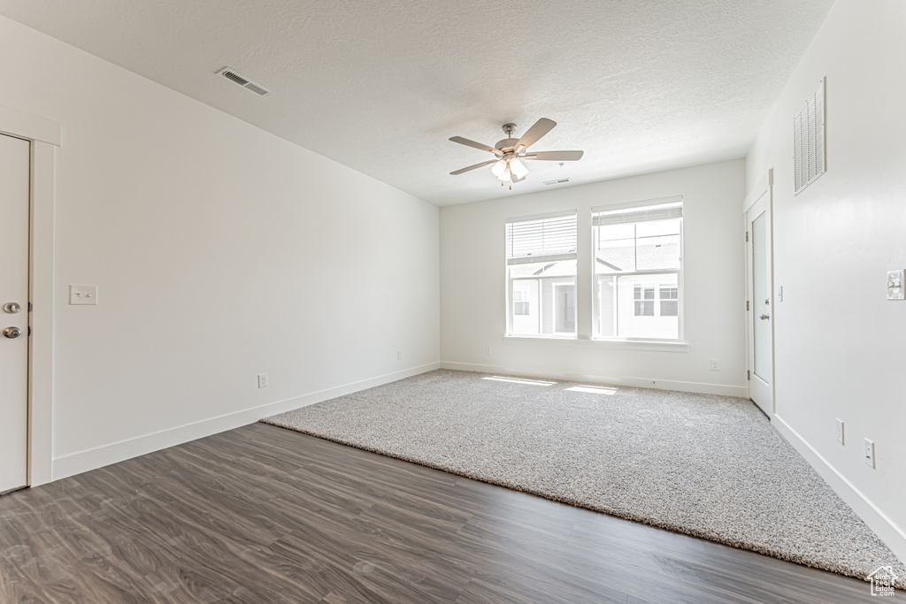 Spare room with ceiling fan, wood finished floors, and a textured ceiling
