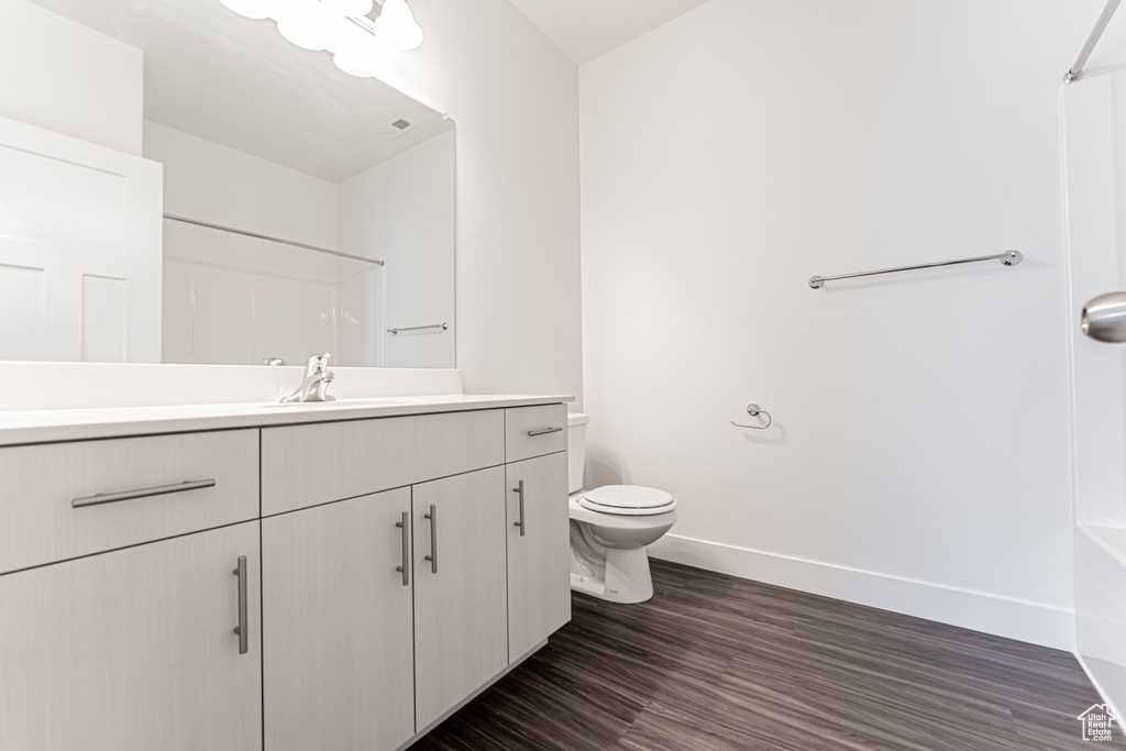 Full bath with vanity, a shower, and wood finished floors