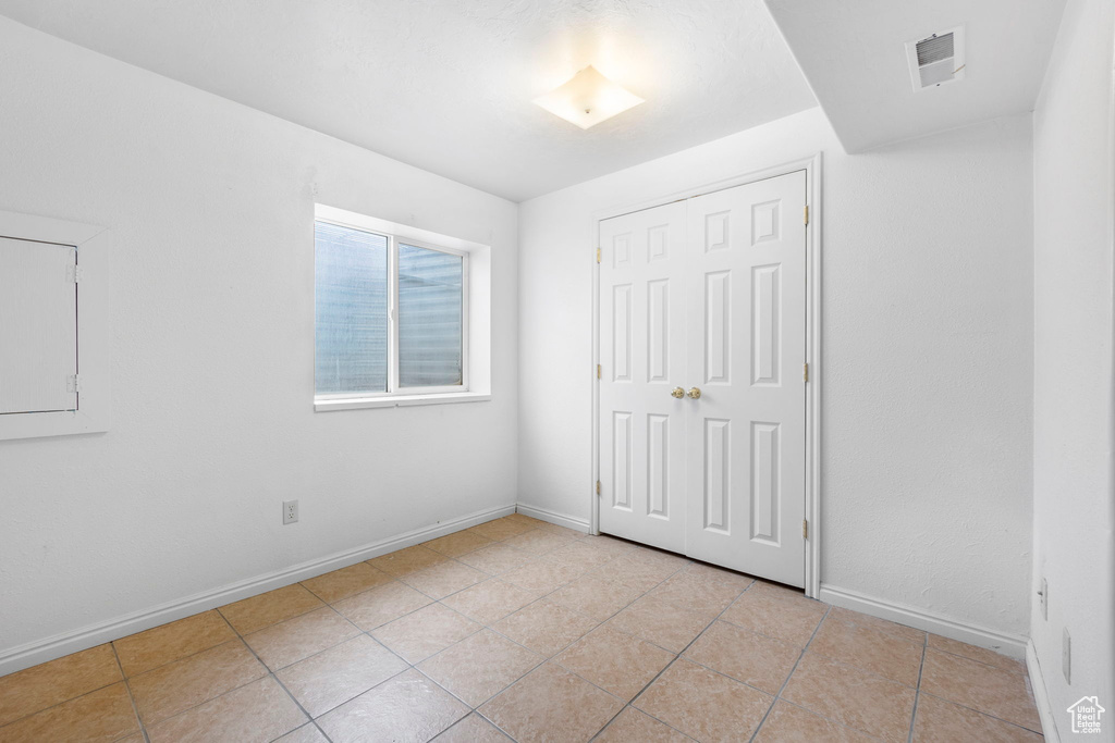 Unfurnished bedroom featuring a closet and light tile patterned floors