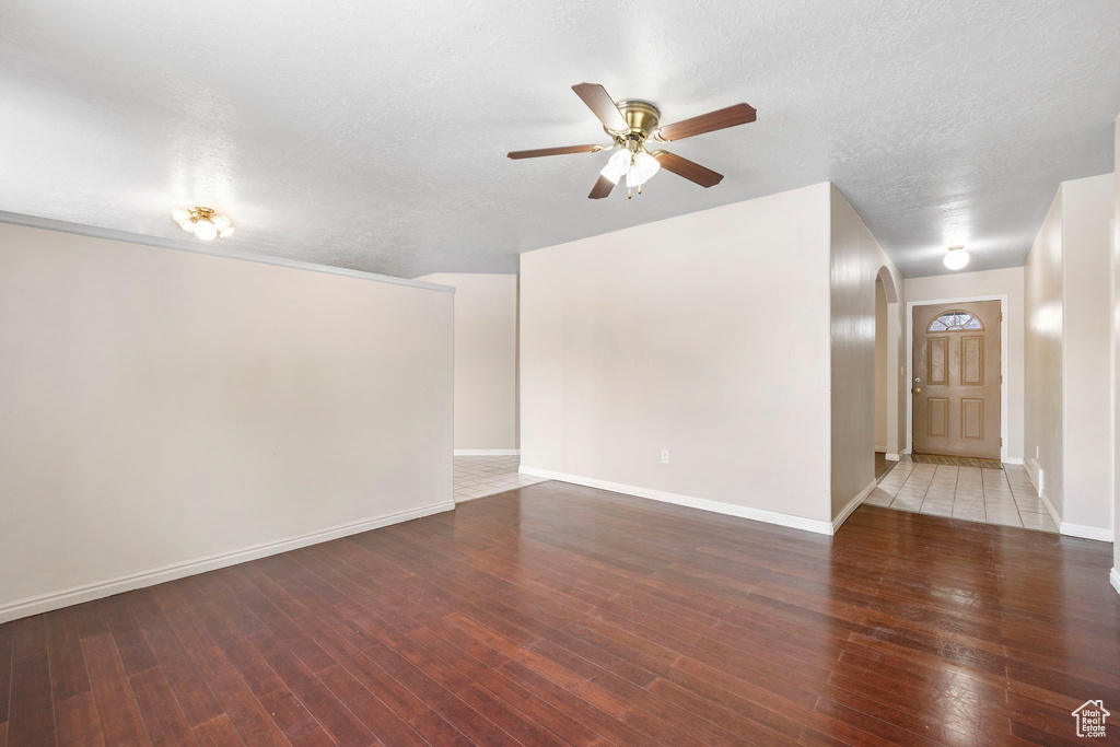 Empty room with ceiling fan, wood-type flooring, and a textured ceiling