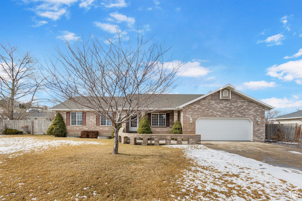 Single story home featuring a garage and a lawn