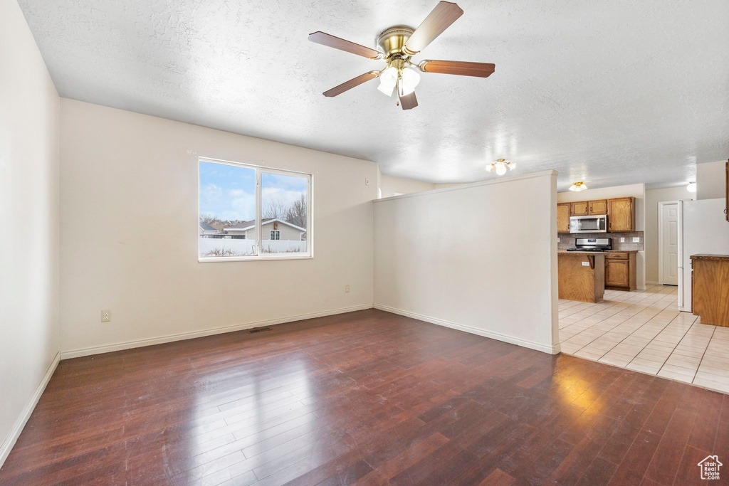 Unfurnished living room with ceiling fan, light hardwood / wood-style flooring, and a textured ceiling