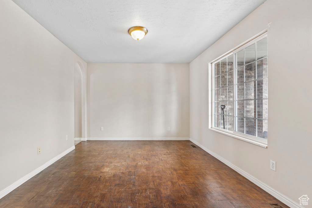 Empty room featuring a textured ceiling and dark parquet flooring