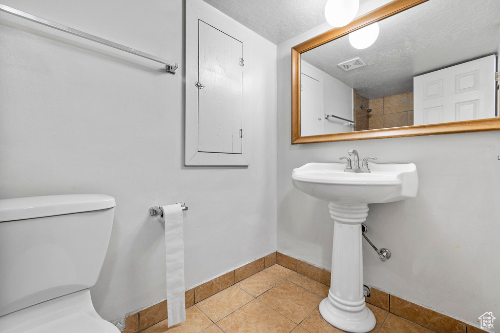 Bathroom featuring tile patterned flooring, toilet, and a textured ceiling