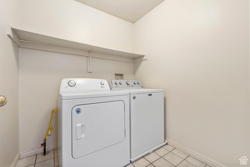 Laundry area featuring washing machine and dryer and light tile patterned floors