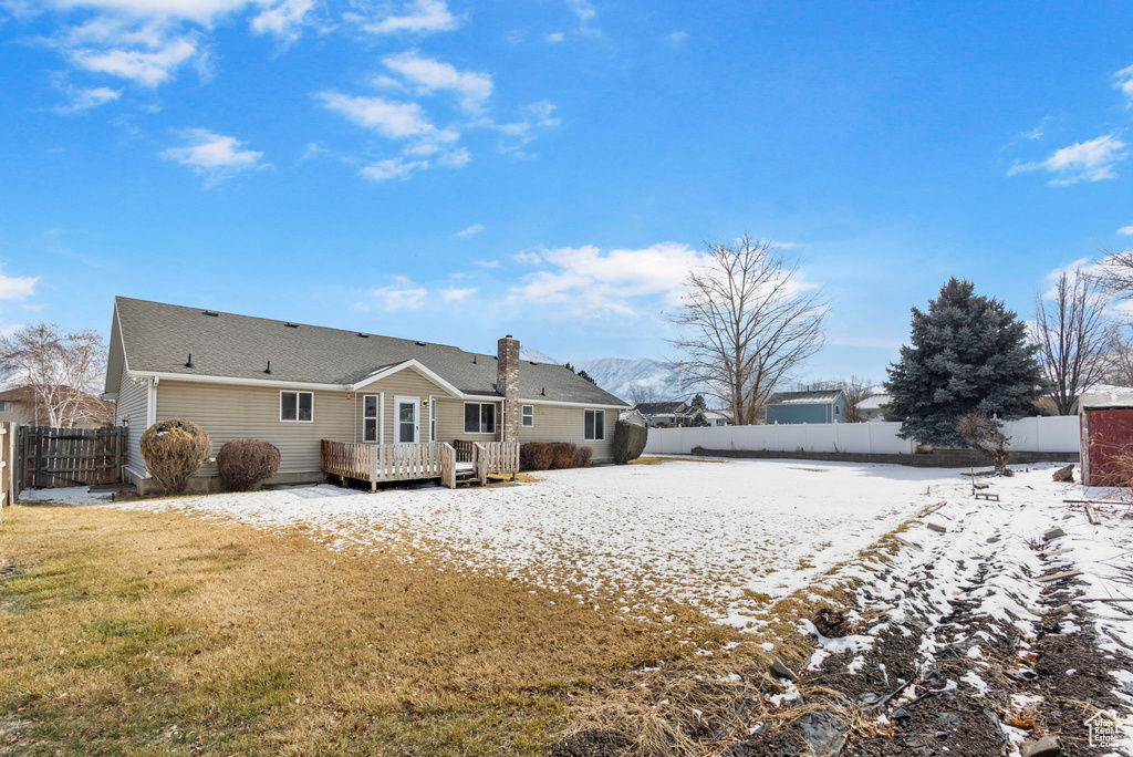 Snow covered property with a lawn and a wooden deck