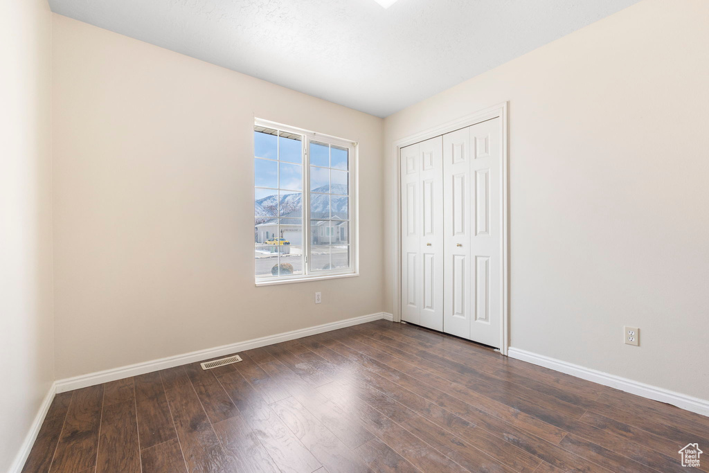 Unfurnished bedroom with a closet and dark hardwood / wood-style floors