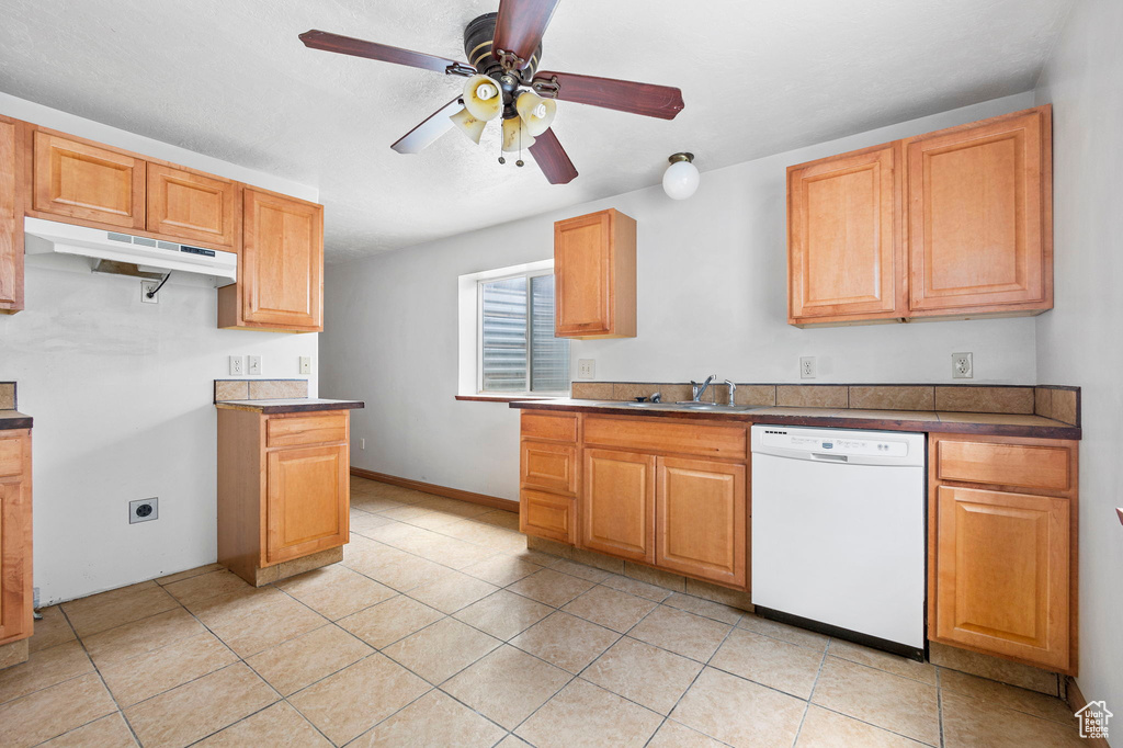 Kitchen featuring sink, light tile patterned floors, ceiling fan, and dishwasher