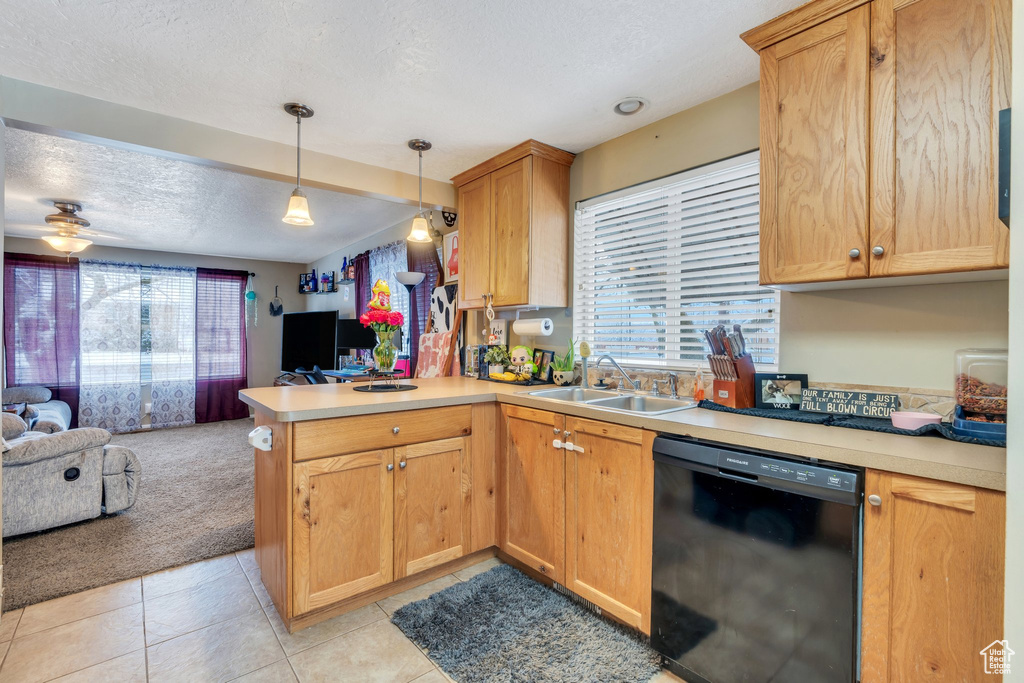 Kitchen featuring pendant lighting, black dishwasher, sink, light tile patterned floors, and kitchen peninsula