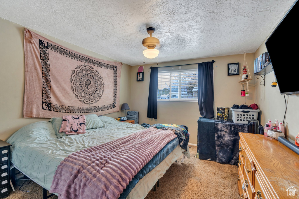 Bedroom with ceiling fan, light carpet, and a textured ceiling