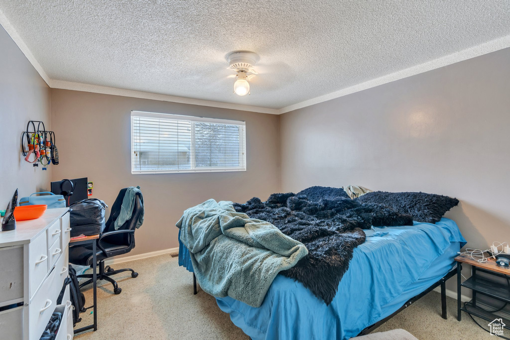 Bedroom featuring ceiling fan, light colored carpet, ornamental molding, and a textured ceiling