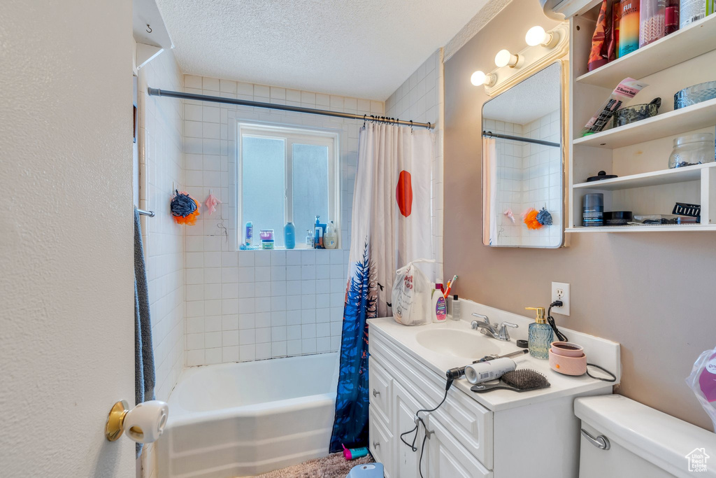 Full bathroom featuring vanity, shower / bath combination with curtain, a textured ceiling, and toilet