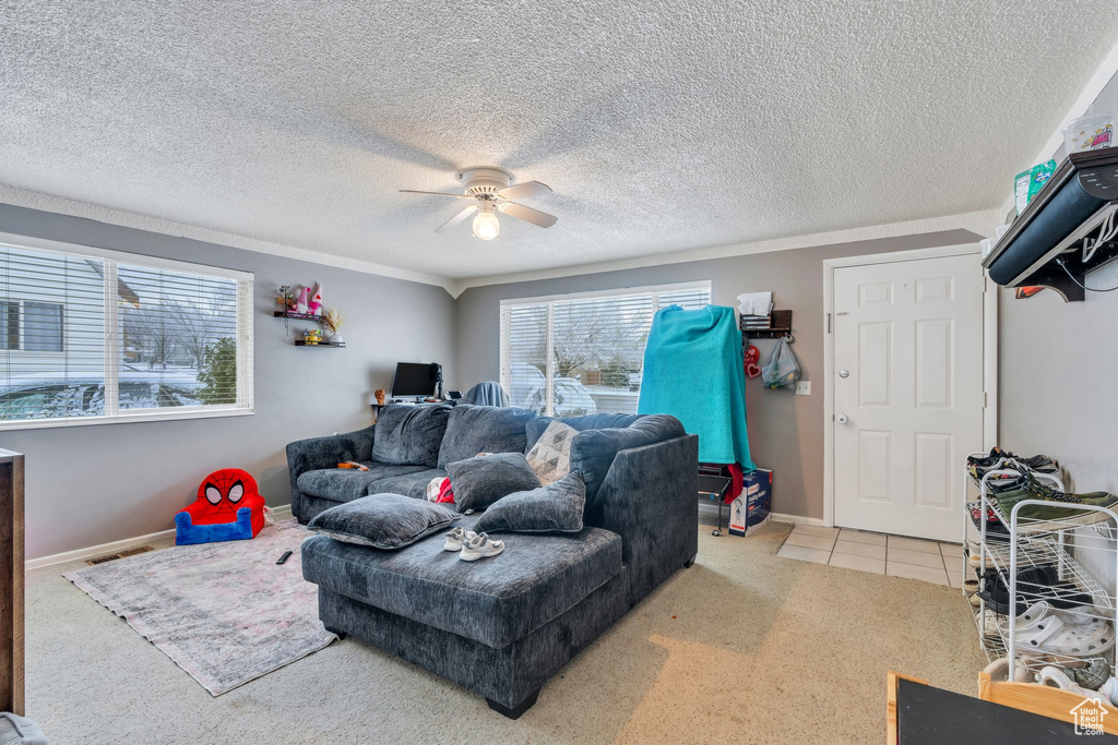 Carpeted living room with a textured ceiling and ceiling fan