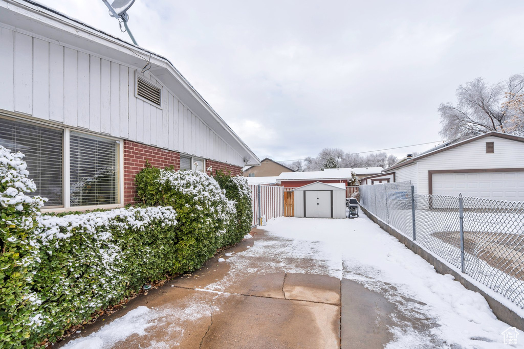 Snow covered property featuring a garage and a shed