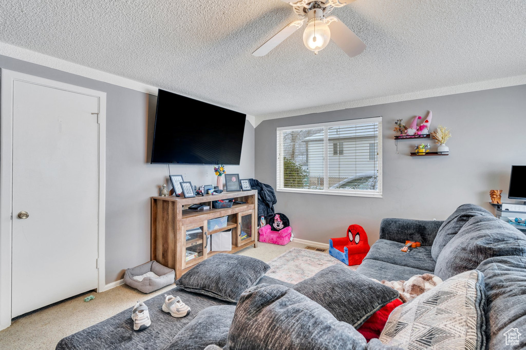 Living room with a textured ceiling, ceiling fan, and carpet flooring