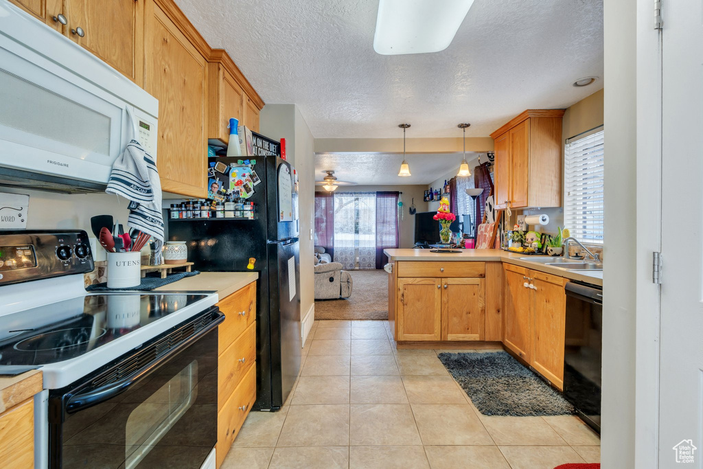 Kitchen featuring light tile patterned flooring, sink, kitchen peninsula, pendant lighting, and black appliances