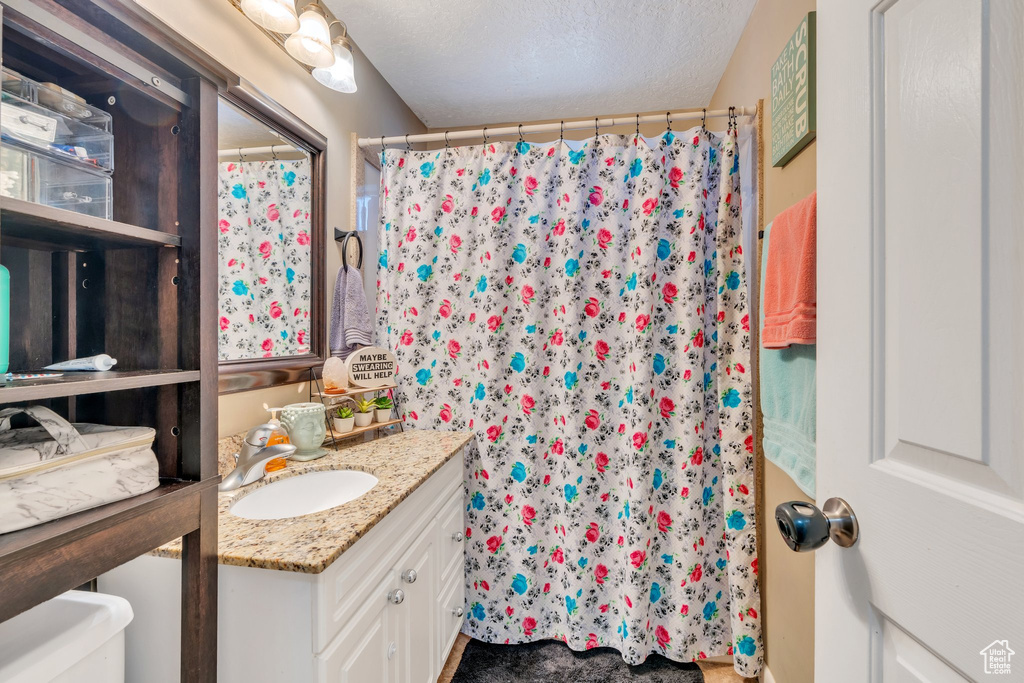 Bathroom featuring a shower with curtain, vanity, toilet, and a textured ceiling