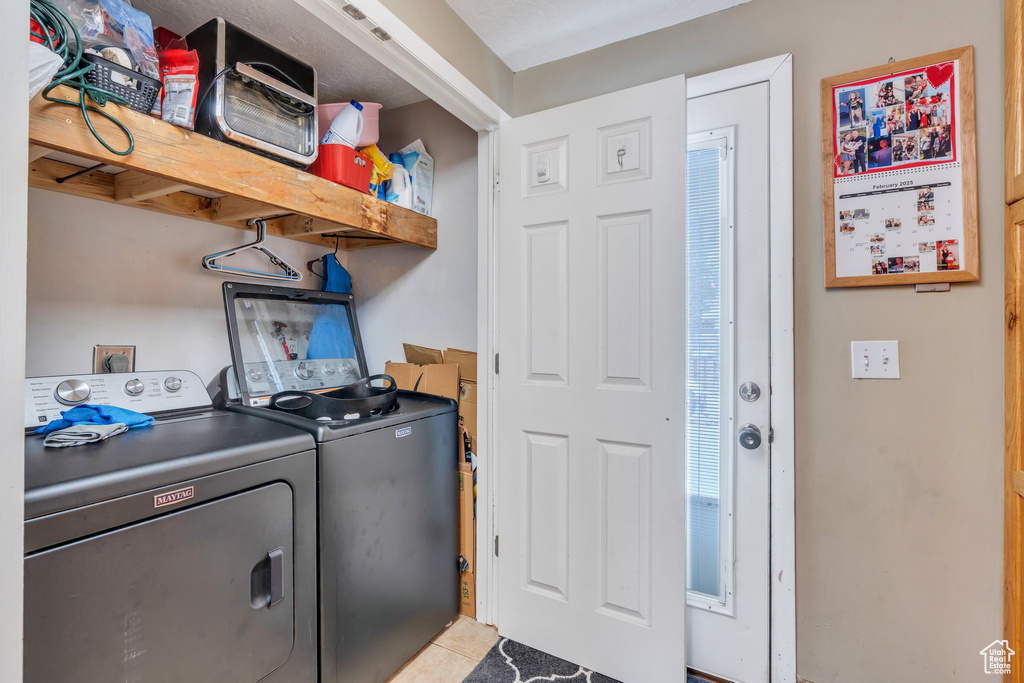 Laundry room with washer and clothes dryer and light tile patterned floors