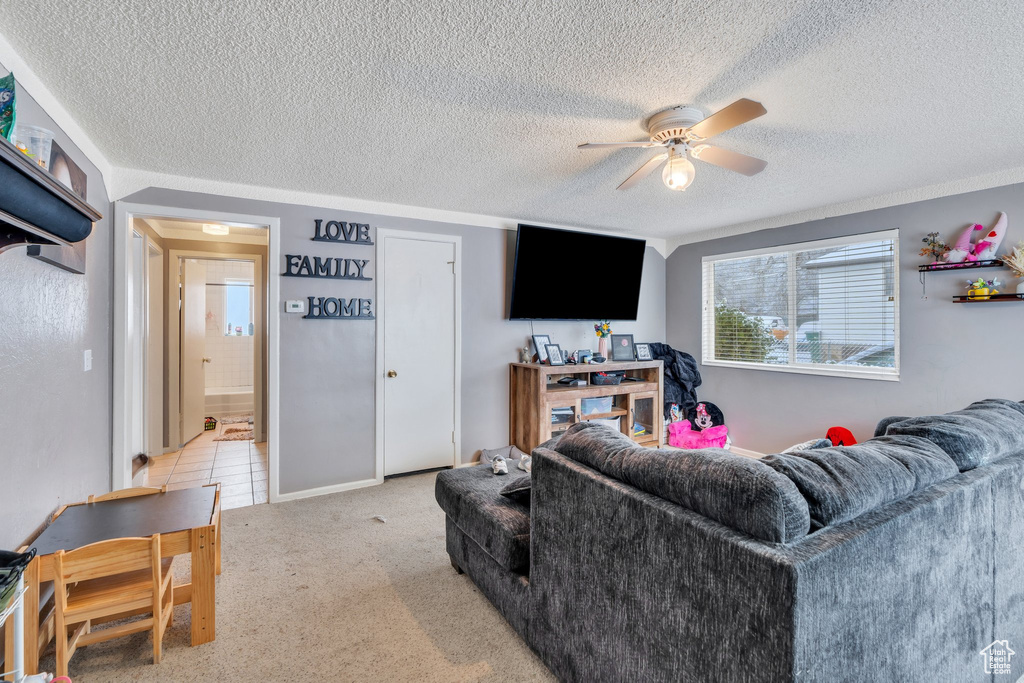 Living room featuring ceiling fan, light carpet, and a textured ceiling